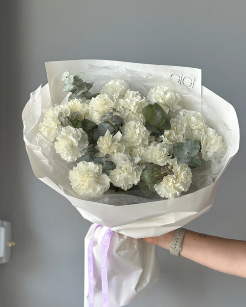 A bouquet of pink carnations wrapped in paper with a visible brand name on the tape.
