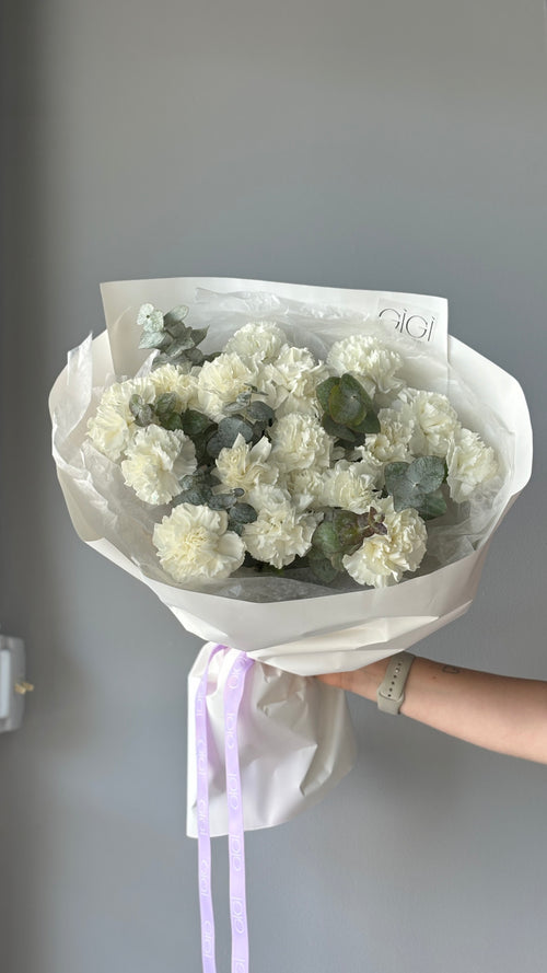 A bouquet of pink carnations wrapped in paper with a visible brand name on the tape.