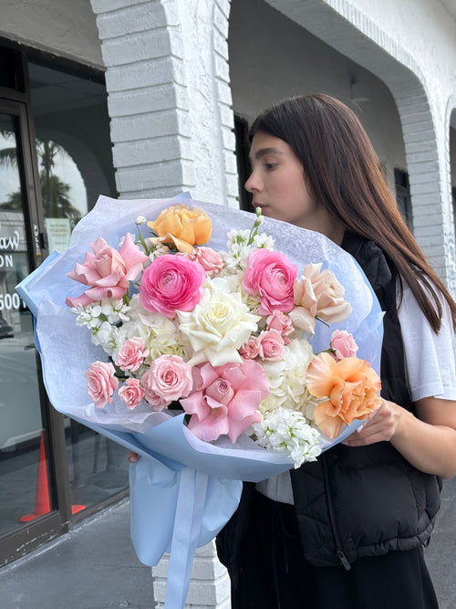 Person holding a large bouquet of flowers on a street.