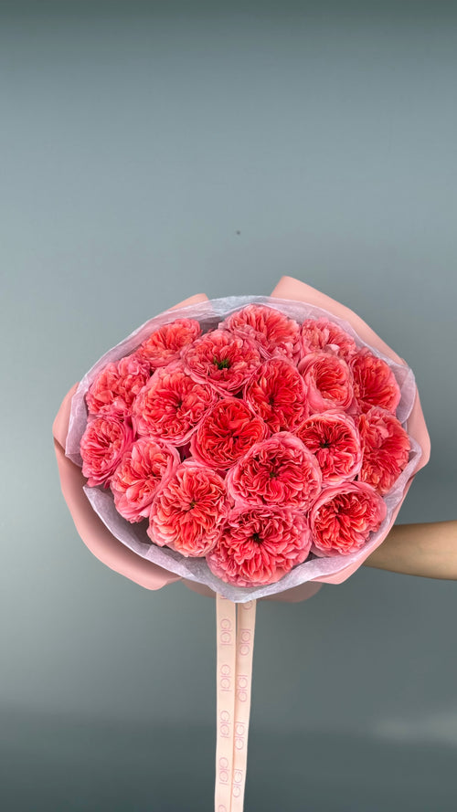 Bouquet of red flowers held by a hand against a gray background