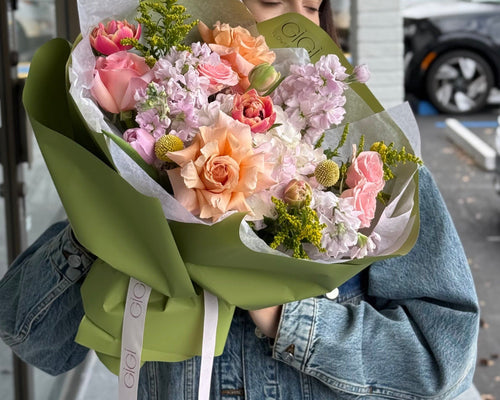 Bouquet of flowers held by a person wearing a denim jacket, with a visible brand label.