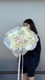 Person holding a large bouquet of white flowers against a plain background