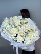 Bouquet of white flowers held by a person against a gray background
