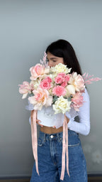 Person holding a bouquet of pink and white flowers against a plain background