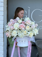 Person holding a large bouquet of flowers in front of a building with 'GIGI Flower Studio' branding.