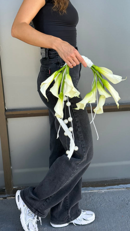 Person holding a bouquet of white flowers against a neutral background