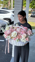 A person holding a basket filled with silk flowers in various colors, arranged as a bouquet.