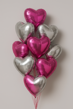 Bouquet of pink and silver heart-shaped balloons on a light gray background