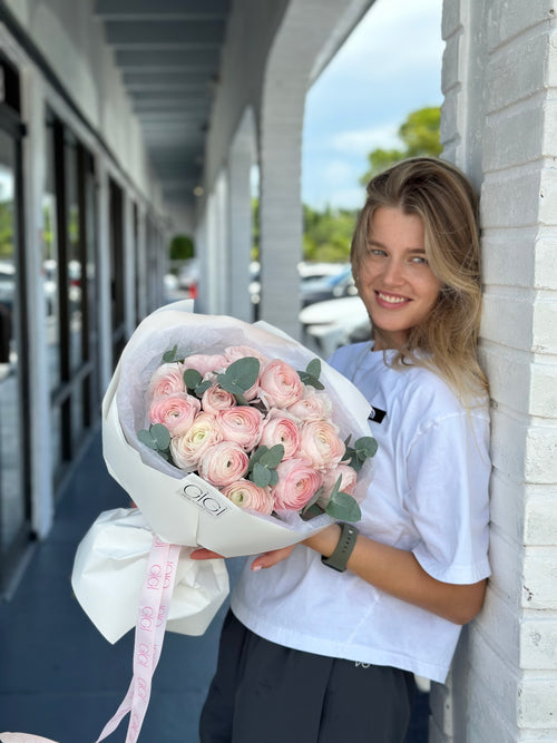 Person holding a large bouquet of pink flowers outdoors.
