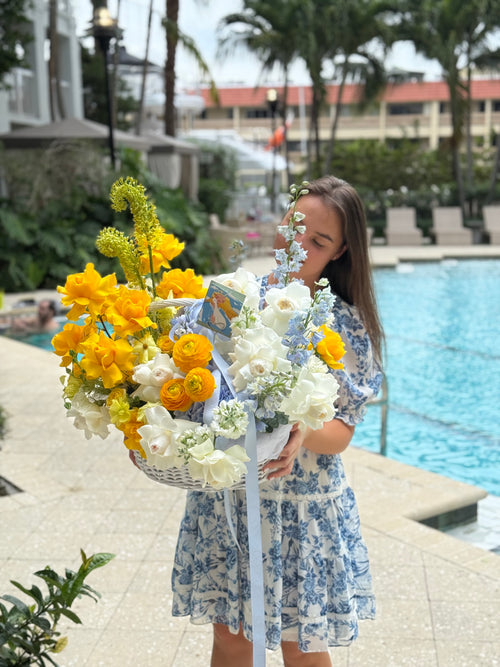 Woman holding a large bouquet of flowers by a poolside