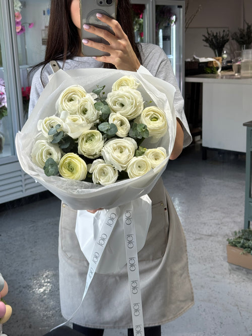 Person holding a large bouquet of white flowers in a store setting.