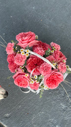 Floral headband with pink flowers and green leaves on a dark surface