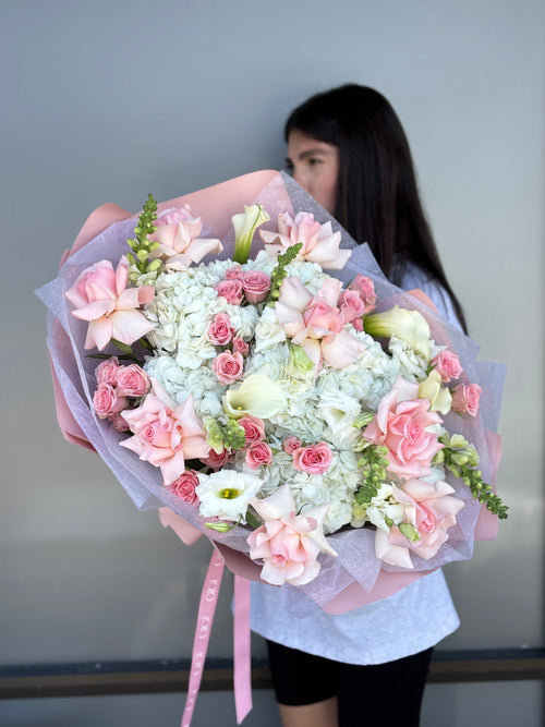 Person holding a large bouquet of flowers with a plain background