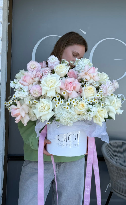 Person holding a large bouquet of flowers with 'Gigi Flower Studio' branding.