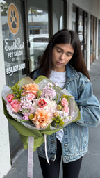 Woman holding a bouquet of flowers in front of a pet salon.