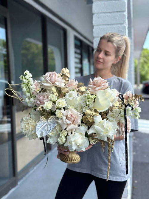 A person holding a bouquet of white and light-colored flowers with decorative elements.