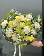 A bouquet of flowers including green hydrangeas, white roses, daisies, and yellow carnations, arranged to resemble a mojito cocktail.