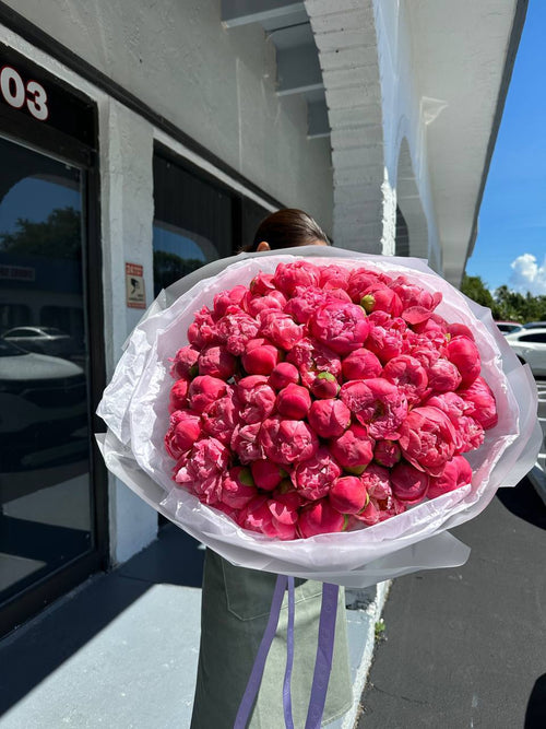 A large bouquet of Coral Charm peonies with vibrant coral-pink color that fading into soft peach