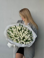 A person holding a large bouquet of white tulips.