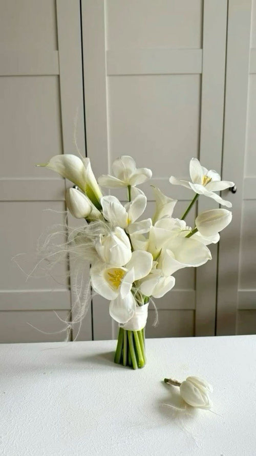 A bouquet of white tulips and calla lilies arranged elegantly on a surface, with a focus on the purity and sophistication they represent.