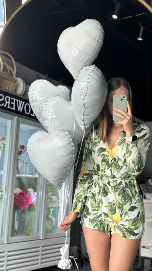 A person holding a bundle of white heart-shaped balloons.