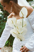 A bride holding an ivory-colored bouquet of flowers, featuring delicate anthuriums, on her wedding day.
