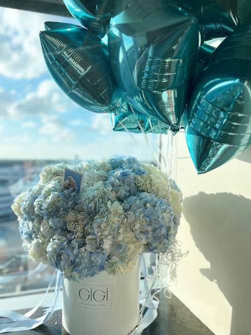 Sky blue and creme bunch of flowers in a basket with balloons