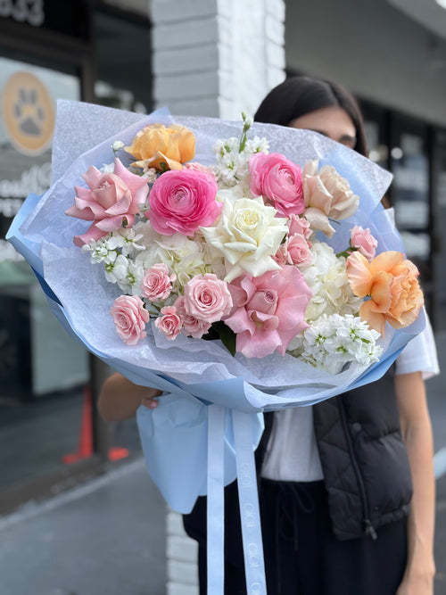 Bouquet of pink, white, and orange flowers held by a person.