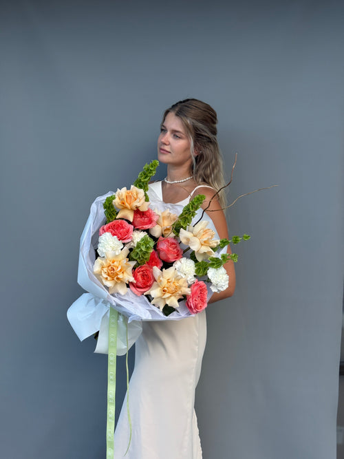 Handcrafted garden rose bouquet featuring coral roses and Bells of Ireland