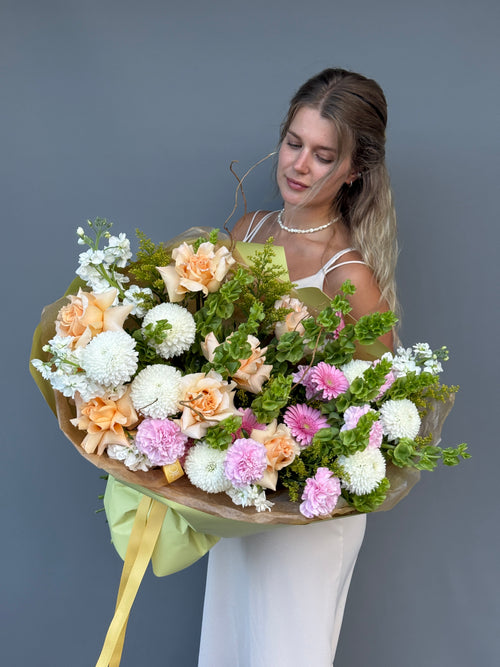 Elegant spring bouquet with peach roses, white chrysanthemums, and green moluccella