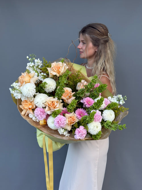 Handcrafted bouquet with premium roses, Bells of Ireland, carnations, and seasonal blooms